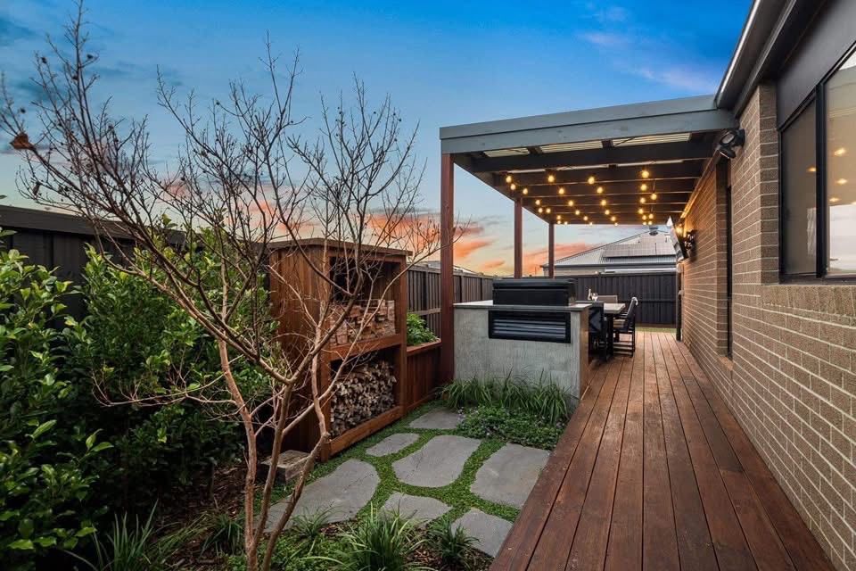 Twilight backyard with alfresco, decking and stone path by Greener Outdoors